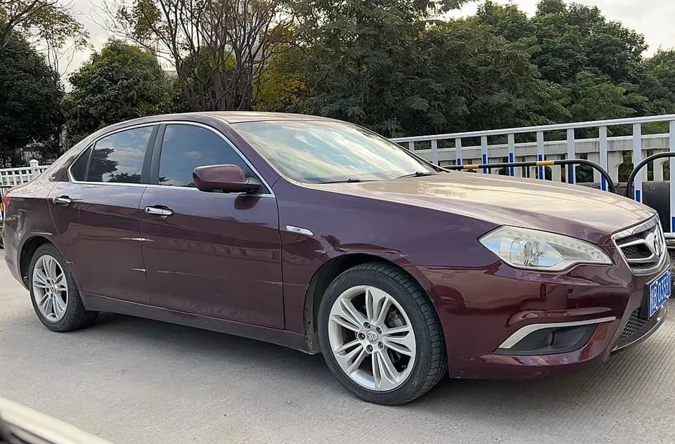 Sedã Senova D70, da BAIC, vinho, estacionado numa rua arborizada