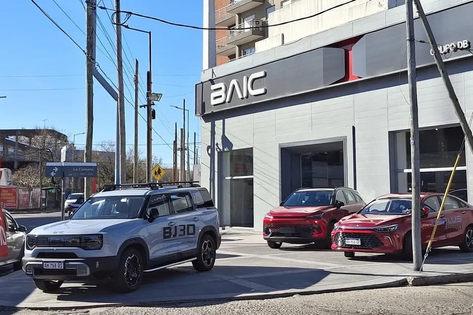 Fachada de uma loja BAIC com um BJ30 prateado e dois SUVs vermelhos estacionados na frente